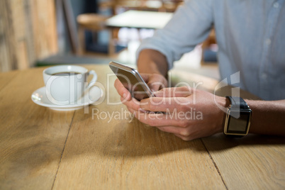 Man using mobile phone at table in coffee shop