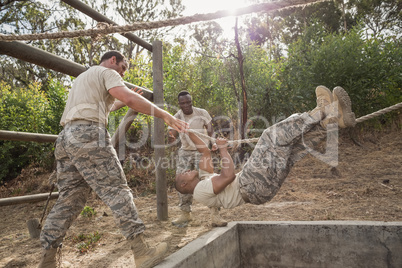 Young military soldiers practicing rope climbing during obstacle course