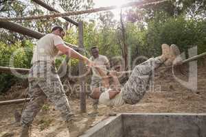 Young military soldiers practicing rope climbing during obstacle course
