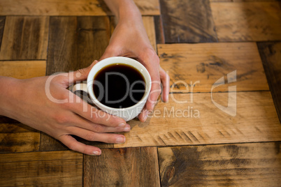 Man holding coffee cup at table in cafe