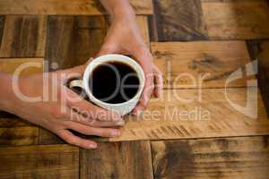 Man holding coffee cup at table in cafe