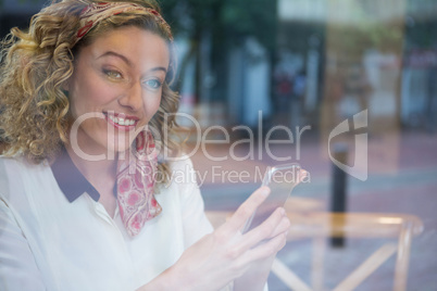 Smiling young woman holding smart phone at cafe