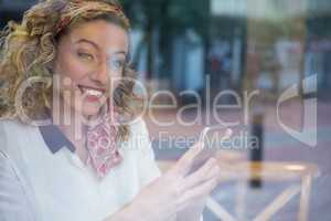 Smiling young woman holding smart phone at cafe