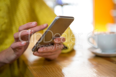 Woman using smart phone at table in coffee shop