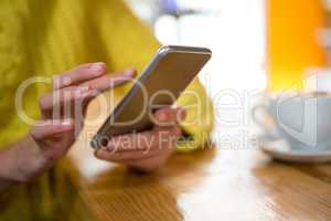 Woman using smart phone at table in coffee shop