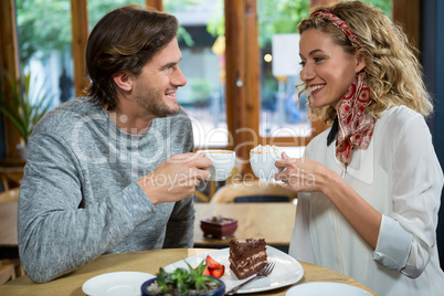 Smiling couple having coffee at table in cafeteria