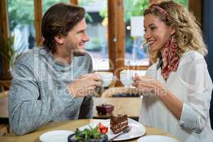 Smiling couple having coffee at table in cafeteria