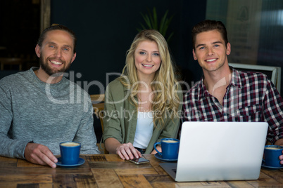 Portrait of friends having coffee at table in cafeteria