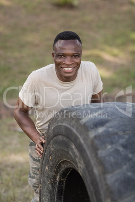 Portrait of happy military soldiers exercising with tyre