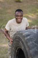 Portrait of happy military soldiers exercising with tyre