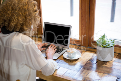 Rear view of woman using laptop in coffee shop