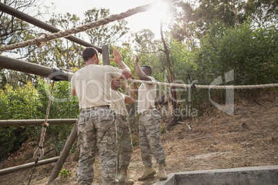Young military soldiers giving after rope climbing during obstacle course