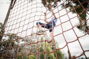 Woman climbing a net during obstacle course