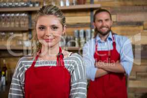 Smiling female barista with male colleague in coffee house