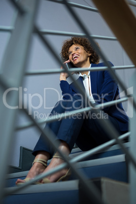 Businesswoman talking on mobile phone while sitting on steps
