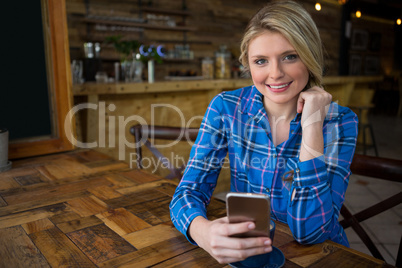 Portrait of smiling woman using mobile phone in coffee shop