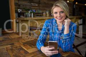 Portrait of smiling woman using mobile phone in coffee shop