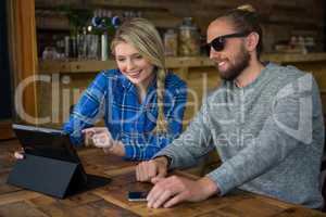 Smiling couple using tablet PC at table in cafe