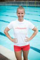 Confident female lifeguard standing at poolside