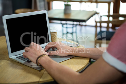 Man using laptop at table in coffee house