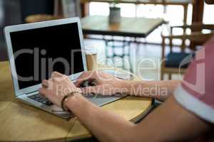 Man using laptop at table in coffee house