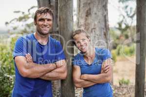 Smiling man and woman standing with arms crossed during obstacle course