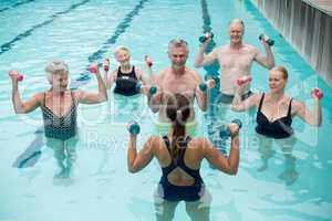 Trainer and senior swimmers exercising in swimming pool