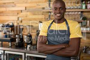 Male barista standing arms crossed in coffee shop