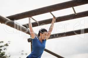 Fit woman climbing monkey bars during obstacle course