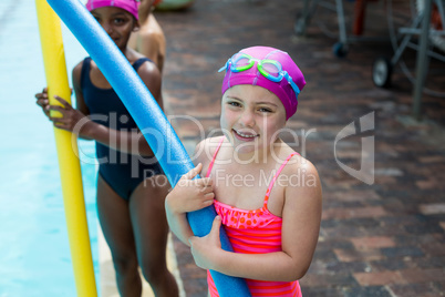 Little girls with pool noodles at poolside