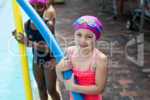Little girls with pool noodles at poolside