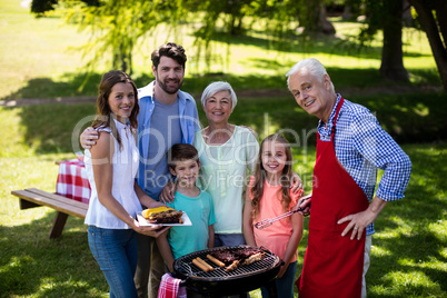 Multi generation family standing near the barbeque in park