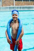 Boy with pool noodle smiling at camera