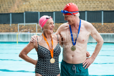 Cheerful senior couple standing at poolside