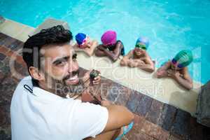 Instructor using stopwatch with little swimmers at poolside