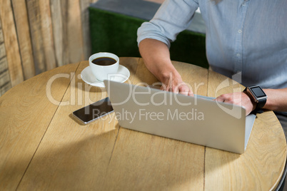 Man using laptop at table in coffee shop