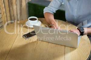 Man using laptop at table in coffee shop