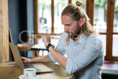 Young man checking time in coffee shop