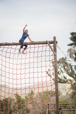 Fit woman with hand raised celebrating success during obstacle course
