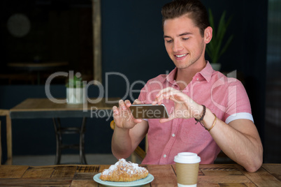 Man photographing food on table in coffee shop