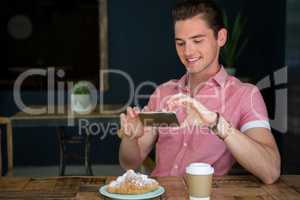 Man photographing food on table in coffee shop