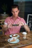 Man photographing food on table in coffee house