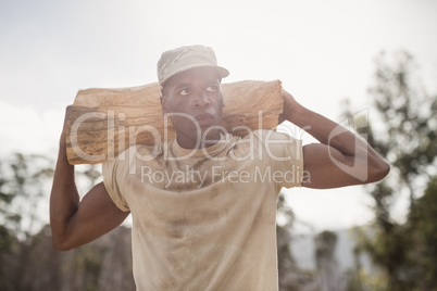 Military soldier carrying a tree log during obstacle course