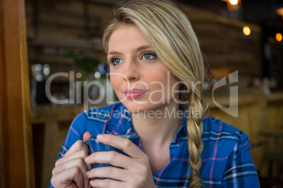 Thoughtful young woman having coffee in cafeteria