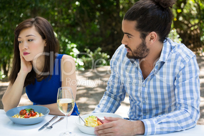 Young man looking at upset woman at restaurant