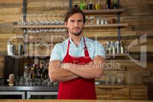 Male barista standing arms crossed in coffee shop