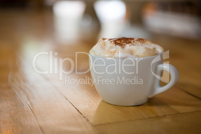 Coffee cup with creamy froth on wooden table