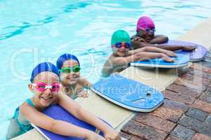 Little swimmers with kickboards at poolside