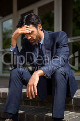 Stressed businessman sitting on steps