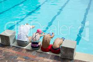 Swimming instructor teaching students at pool side